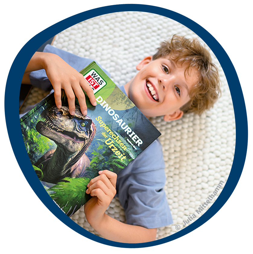lachendes Kind mit WAS IST WAS Dinosaurier
