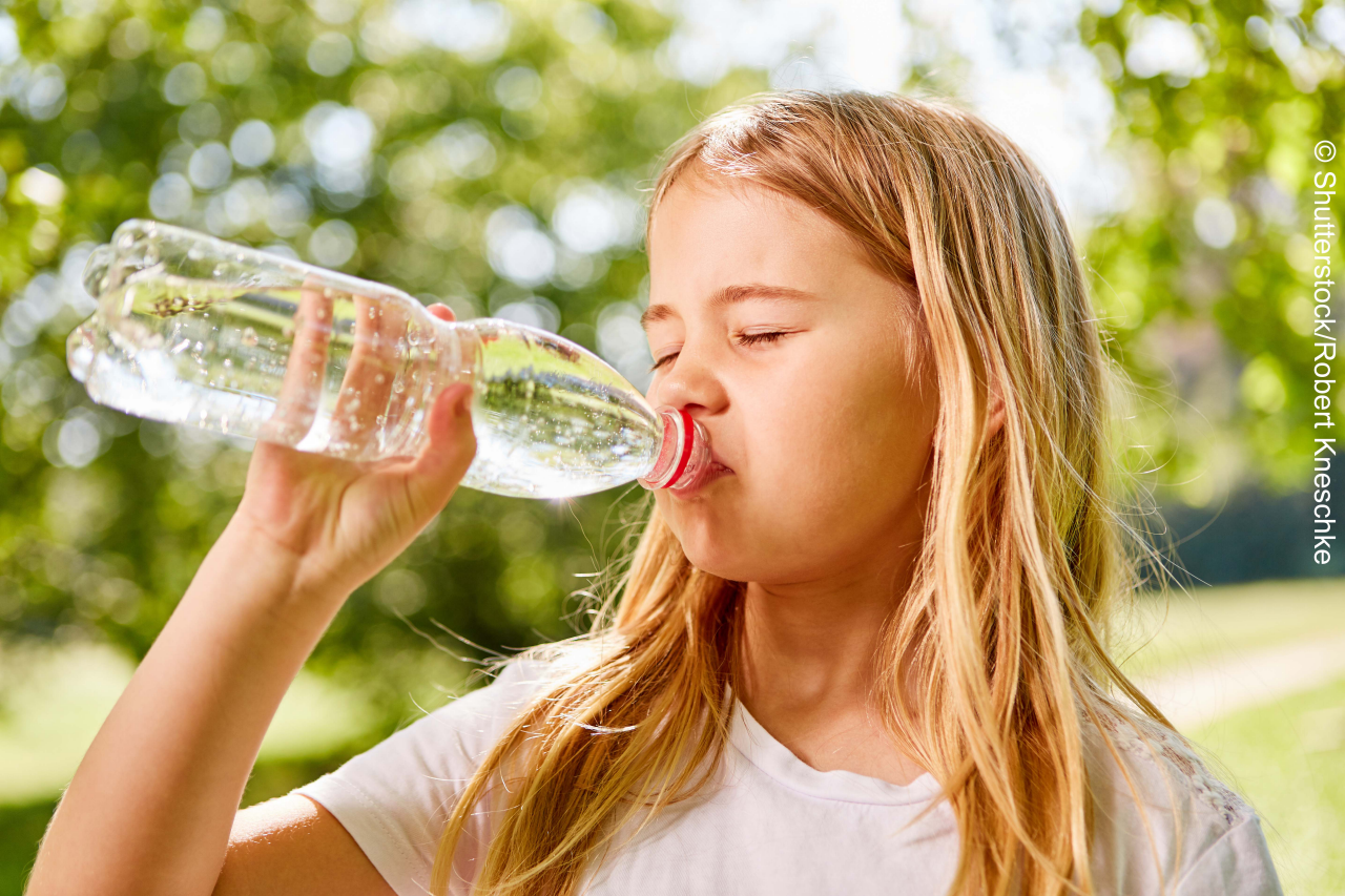 Blonde girl is thirsty and drinks mineral water from a bottle