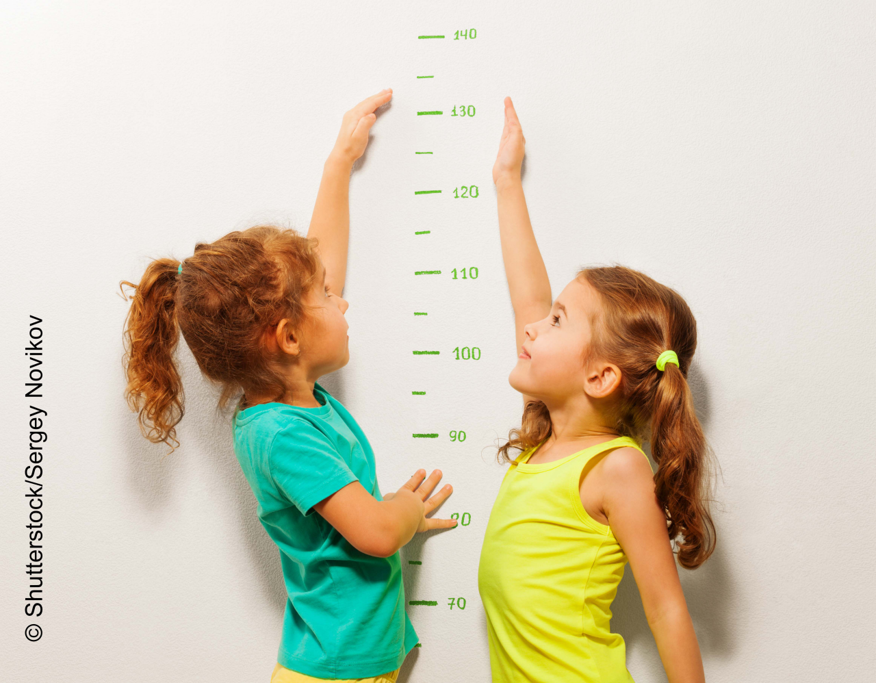 Happy girls stretch hands up on wall scale 